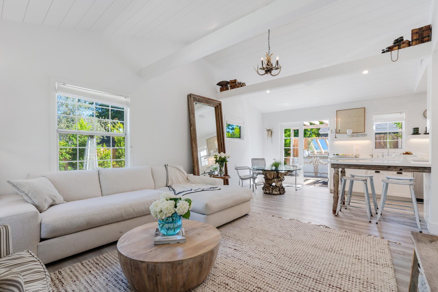 A living room with white furniture and a large mirror.