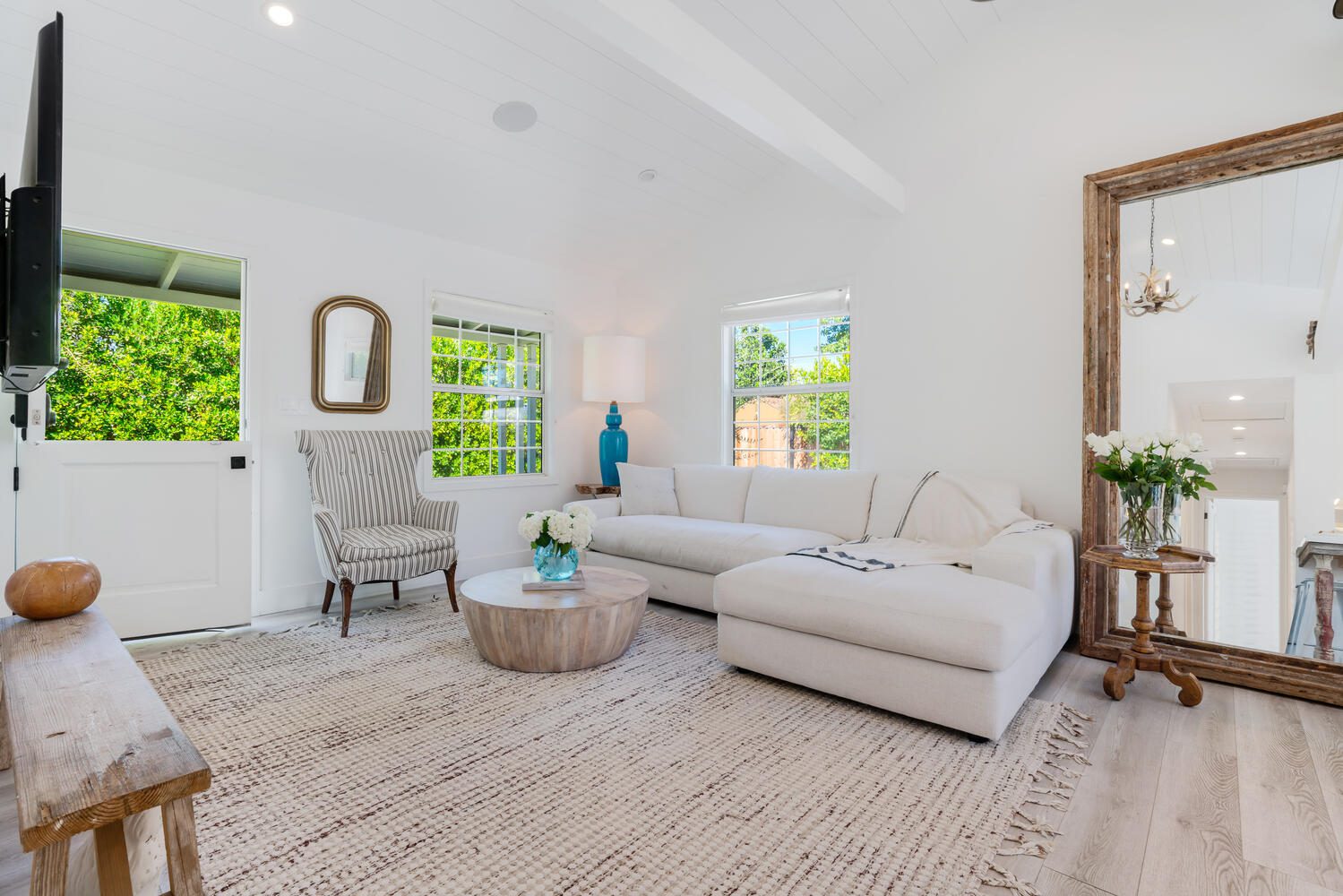 A living room with white furniture and wood floors.