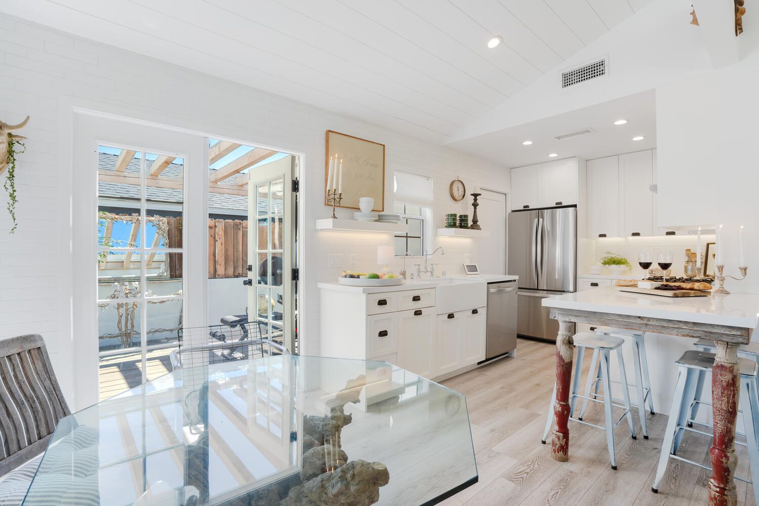 A kitchen with white cabinets and wood floors.