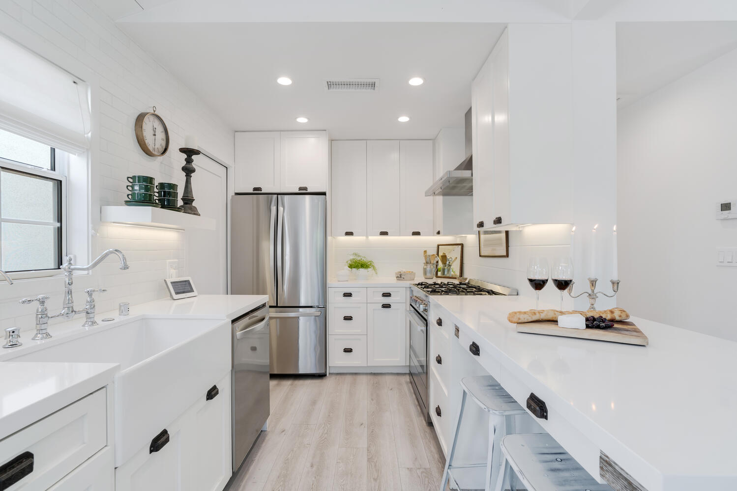 A kitchen with white cabinets and wood floors.