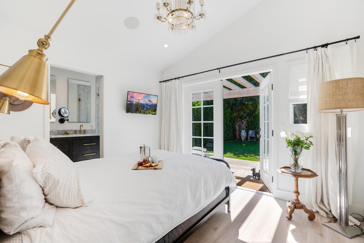 A bedroom with white walls and wooden floors.