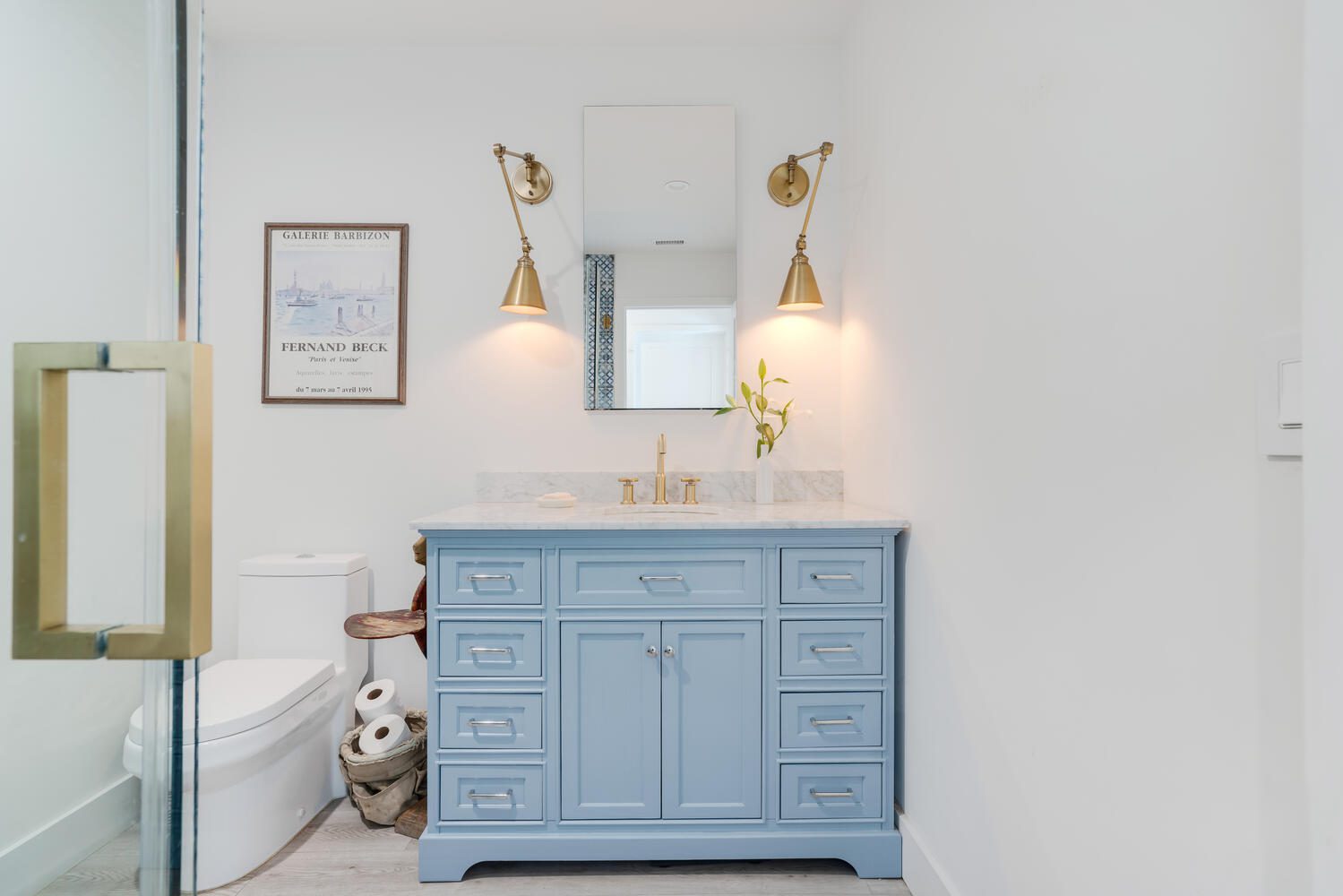 A bathroom with a blue vanity and white walls.