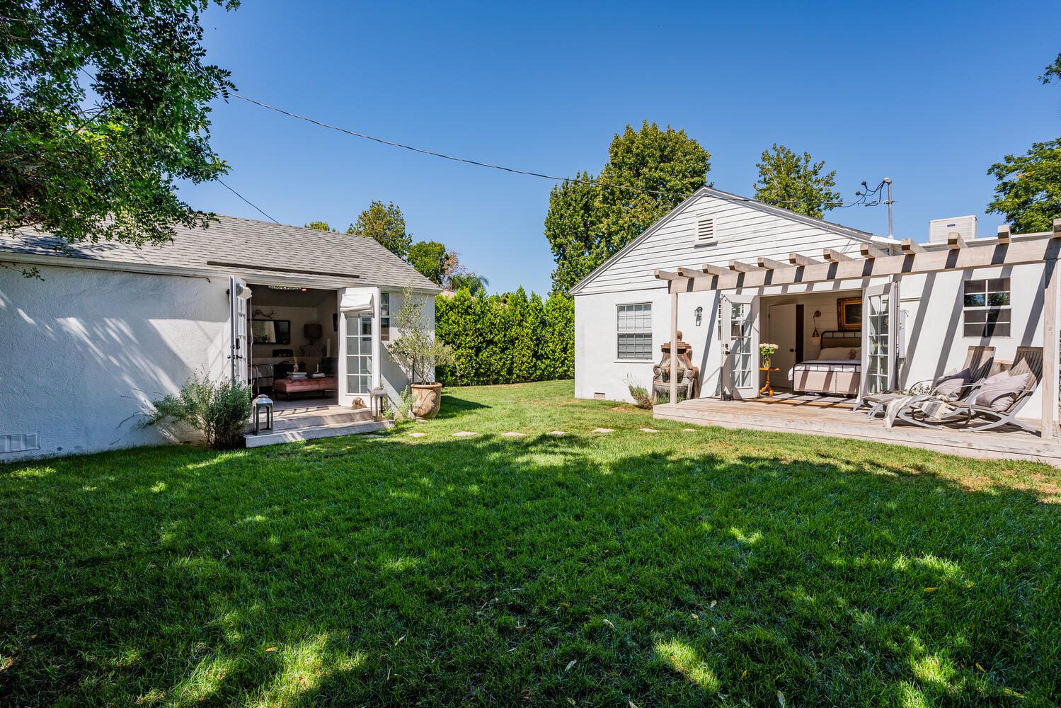 A backyard with two white houses and green grass.