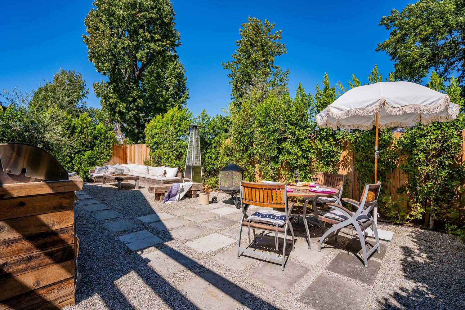 A patio with an umbrella and chairs on the side.