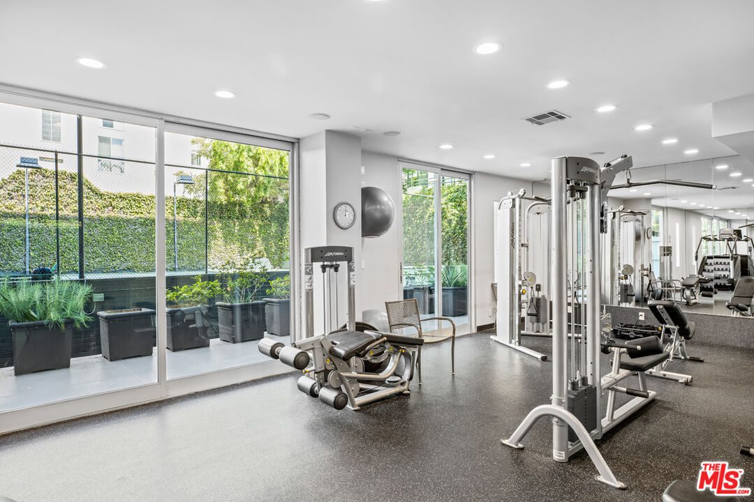 A gym with many machines and large windows.