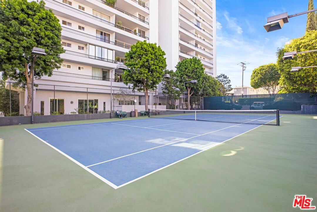 A tennis court with trees and buildings in the background.