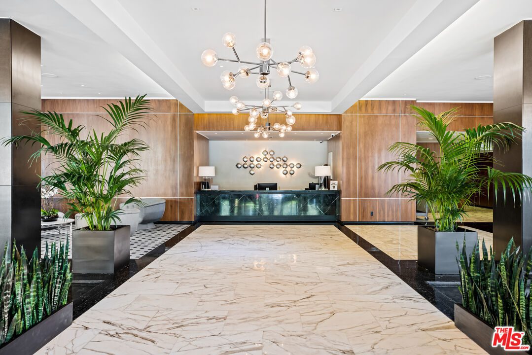 A large lobby with a white carpet and plants.