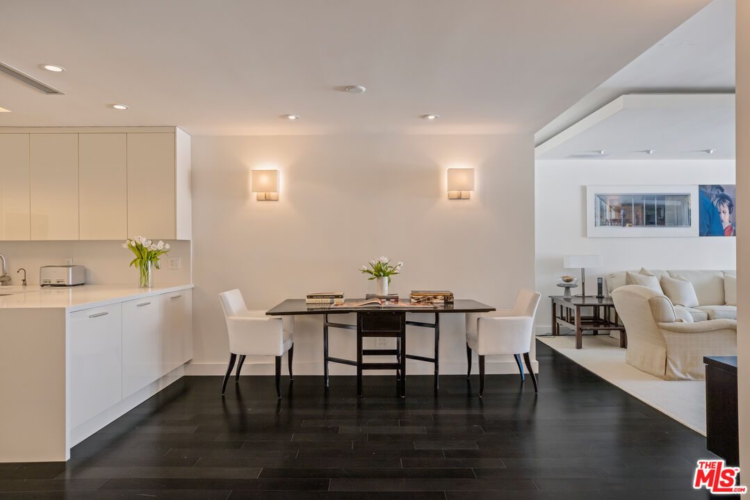 A dining room with white walls and black floors.