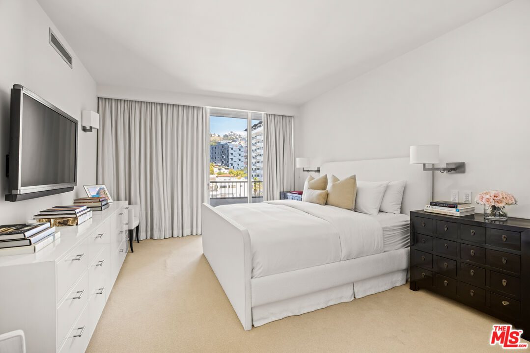 A bedroom with white walls and furniture.