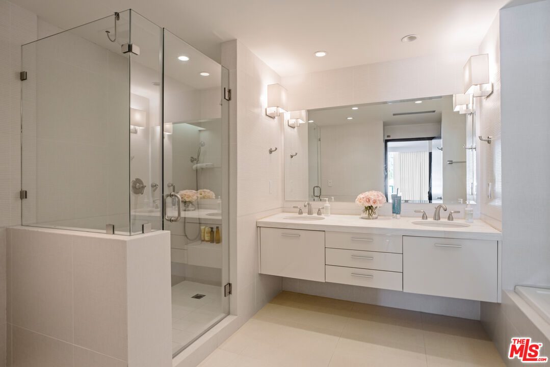 A bathroom with white cabinets and a glass shower door.