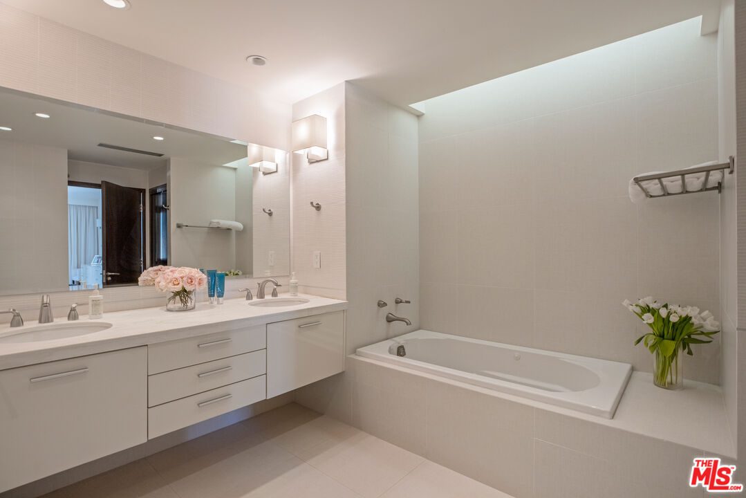 A bathroom with white cabinets and a tub.