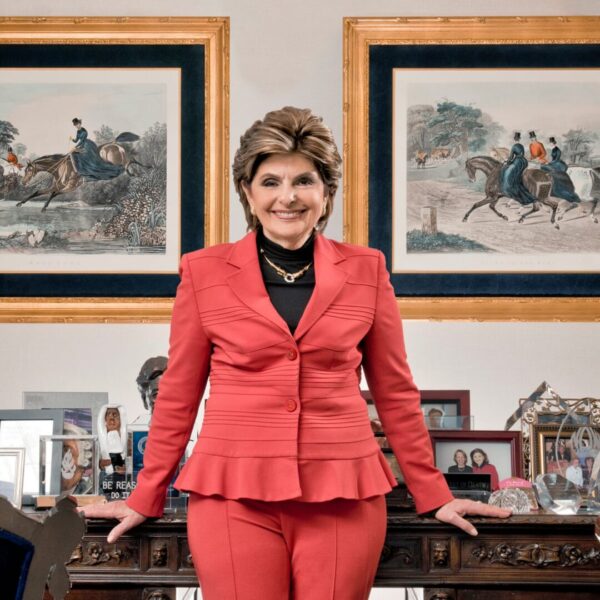 A woman in red suit standing next to a table.