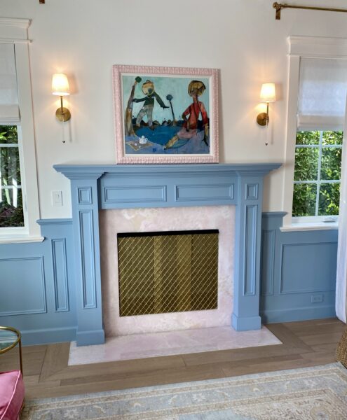 A blue fireplace with white walls and a painting above it.