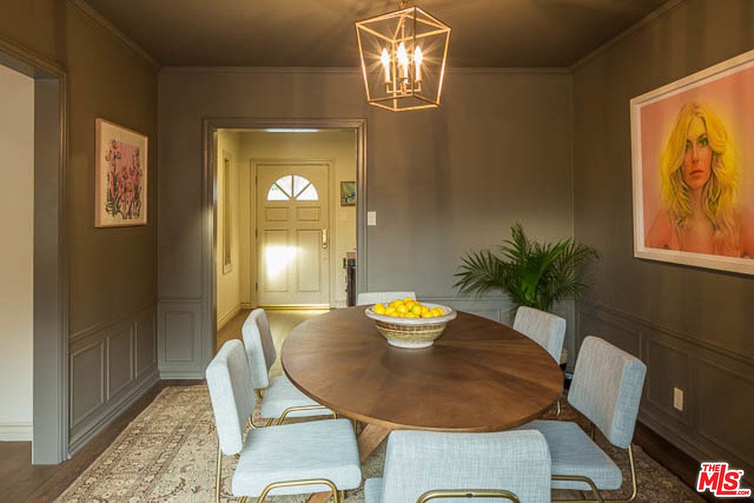 A dining room table with six chairs and a bowl of fruit.