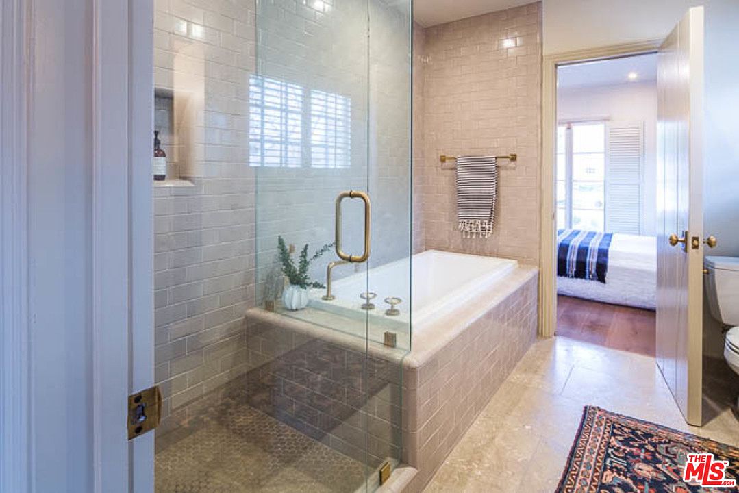 A bathroom with a large tub and glass shower door.