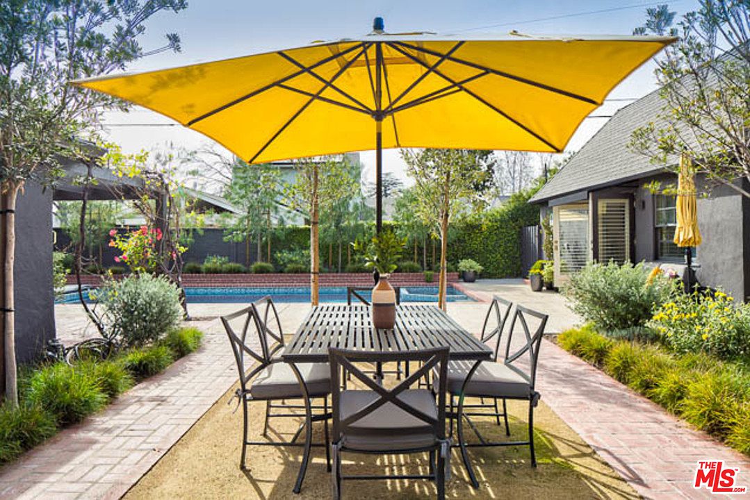 A table and chairs under an umbrella in the sun.