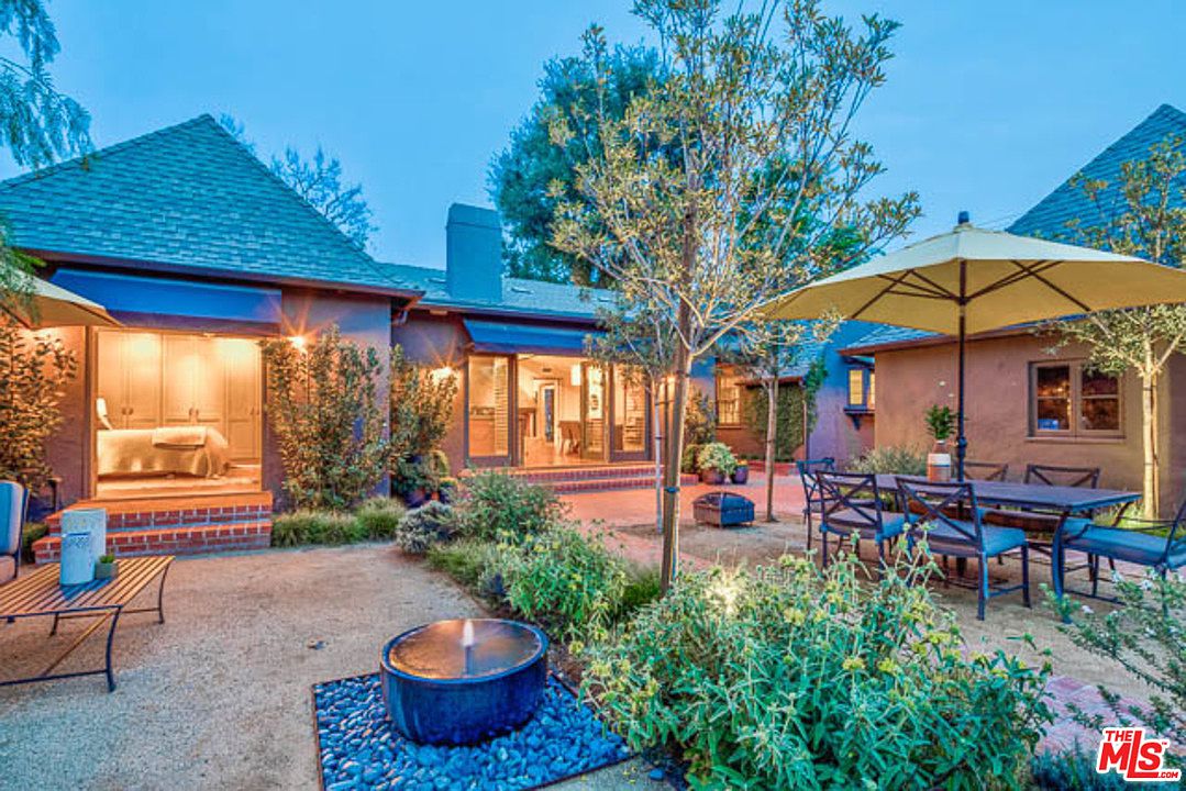 A patio with an umbrella and fire pit in the middle of it.