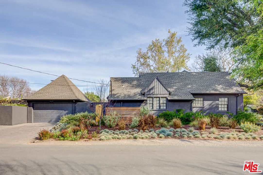 A house with many plants growing in front of it.