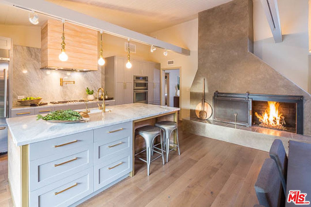 A kitchen with a fireplace and wooden floors