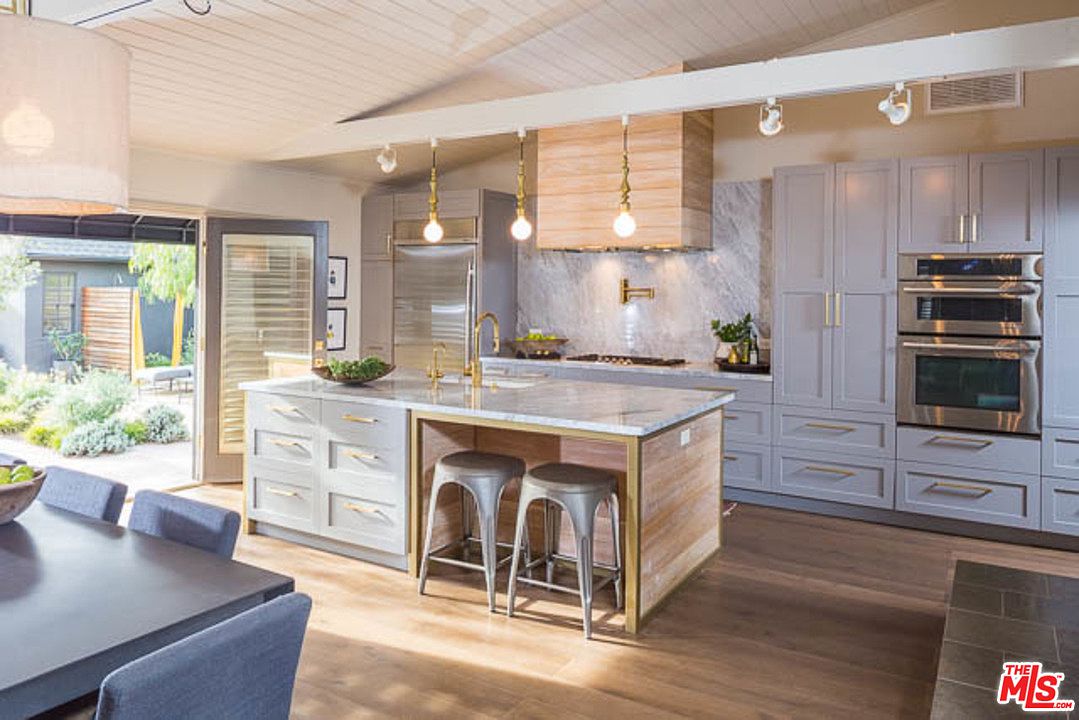 A kitchen with white cabinets and wooden floors.