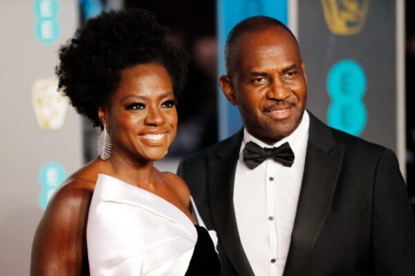 A man and woman in black suits posing for the camera.