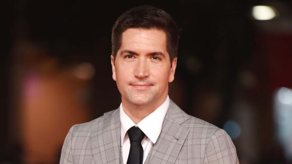 A man in a suit and tie smiling for the camera.