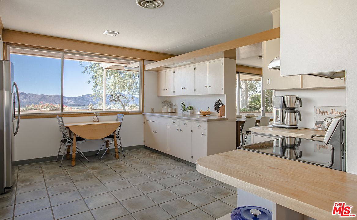 A kitchen with white cabinets and tile floors.