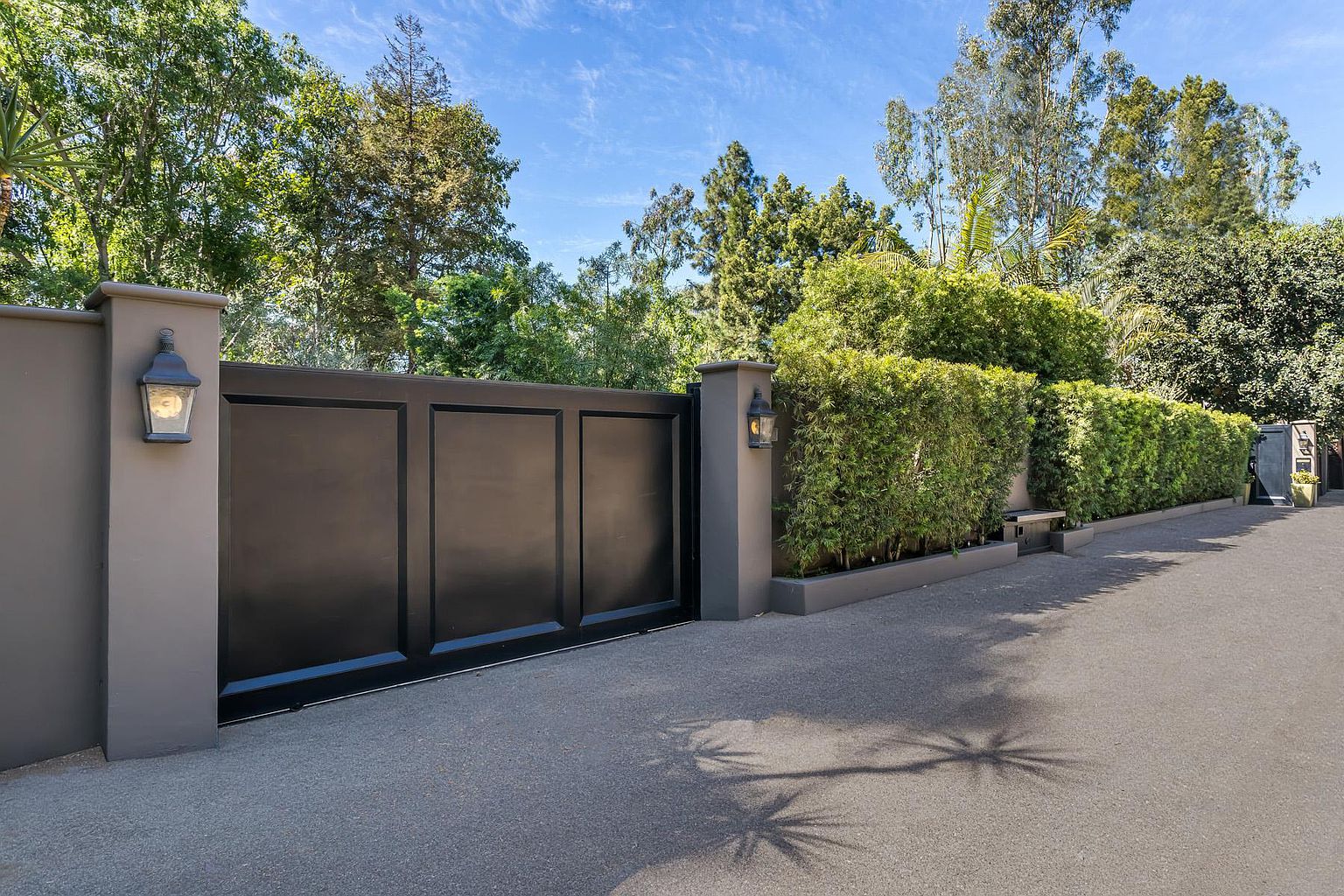 A gated driveway with trees in the background.