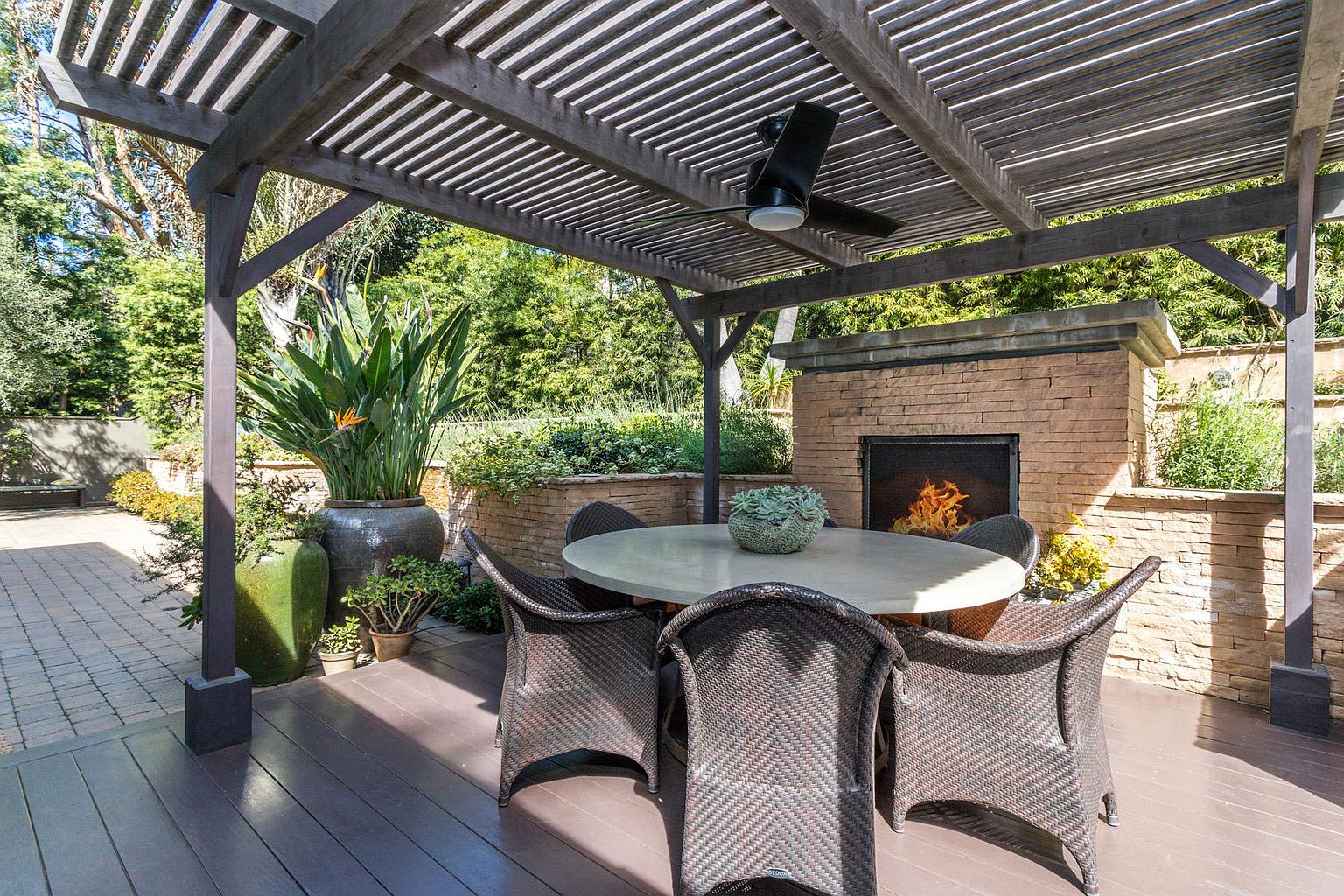 A patio with a table and chairs, fireplace and gazebo.