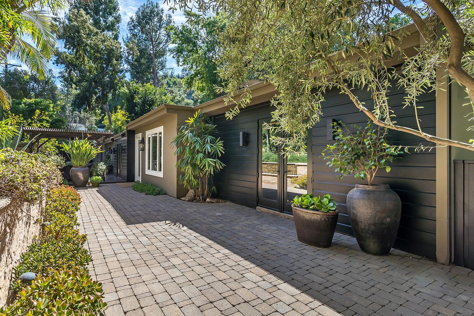 A paved walkway leading to a house with trees.