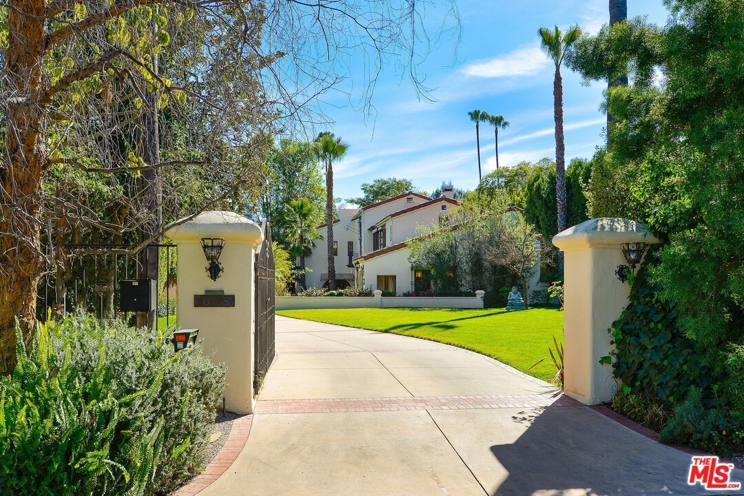 A driveway with a gate and trees in the background.