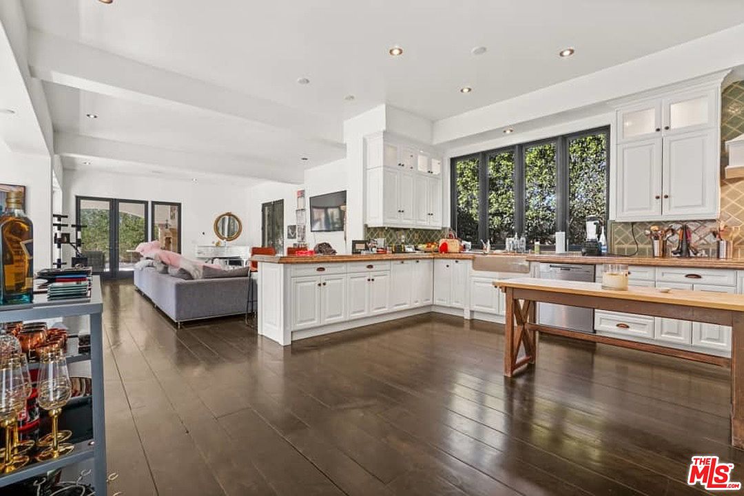 A large open living room with hardwood floors and white cabinets.