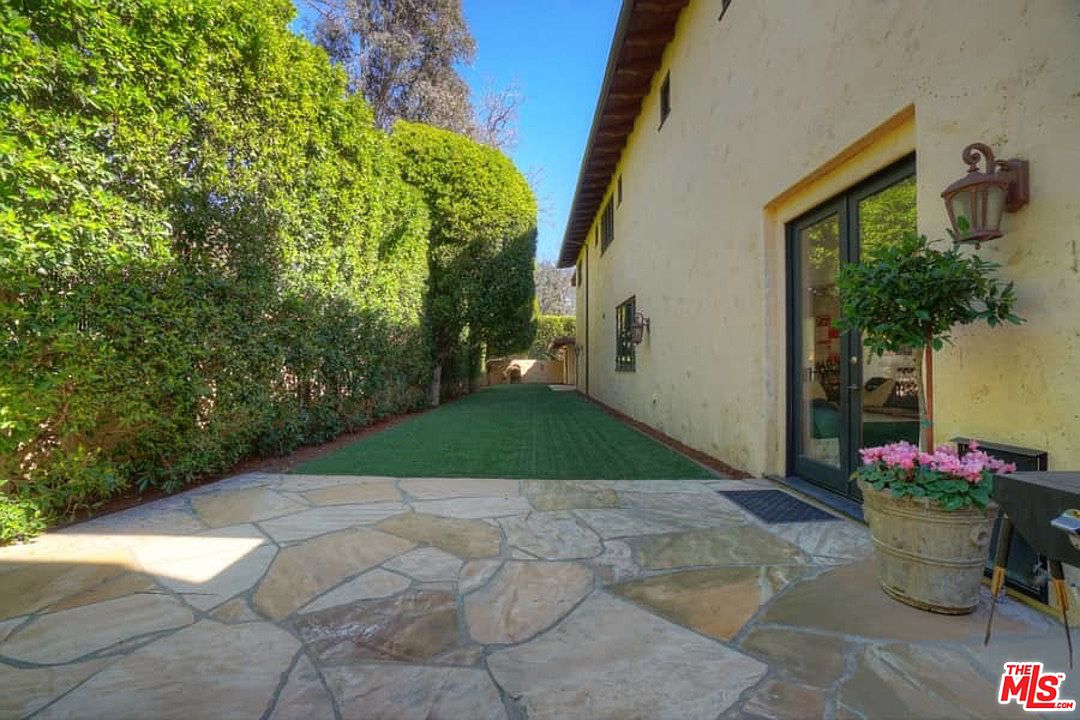 A large patio with grass and trees in the background.