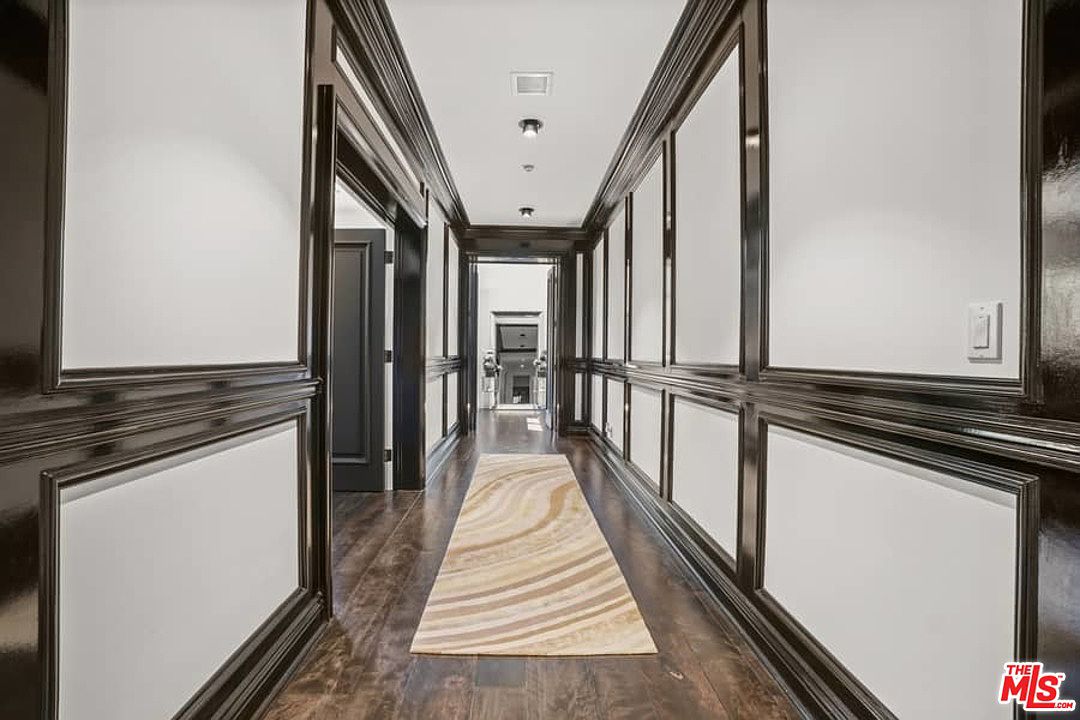 A hallway with two wooden paneled walls and a rug.