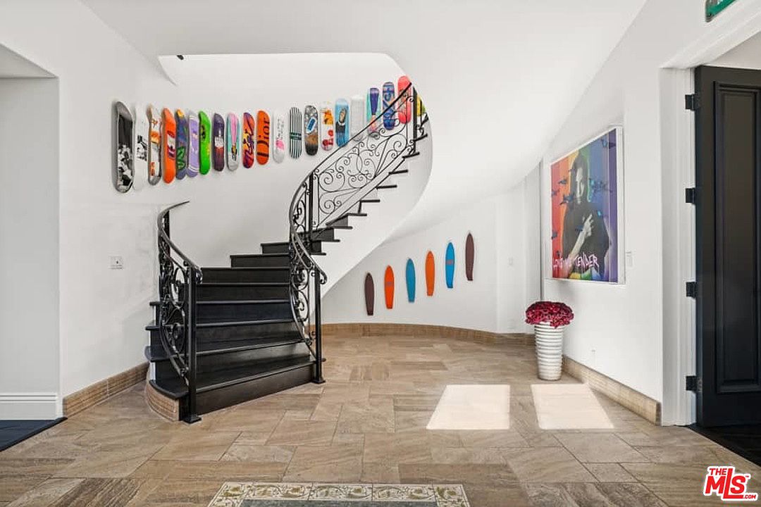 A staircase with black railing and colorful art on the wall.