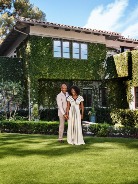 A man and woman standing in front of a house.