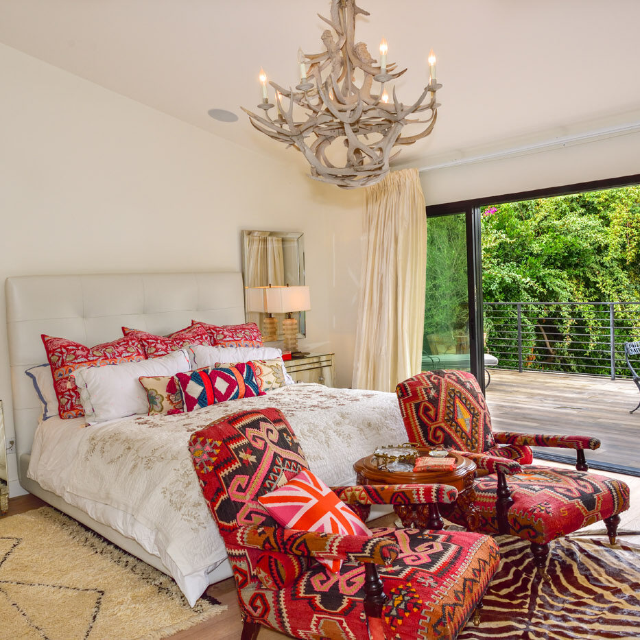 A bedroom with a bed, chair and chandelier.