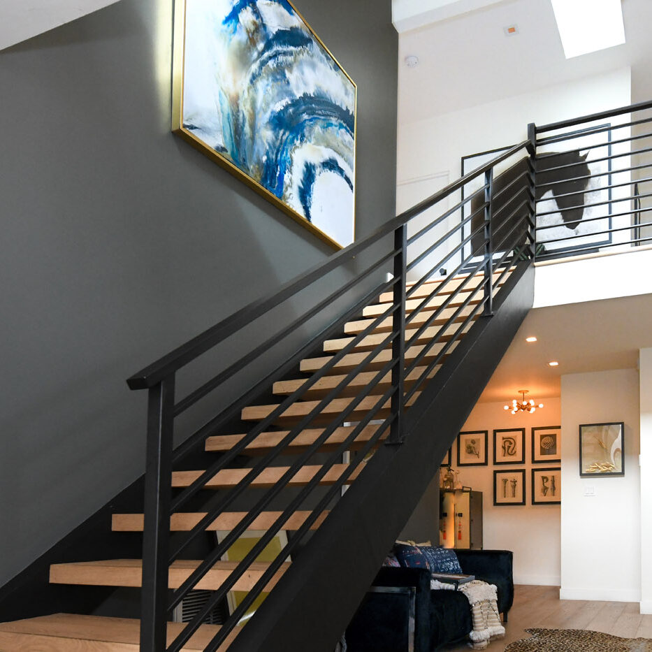 A staircase with metal railing and black handrail.